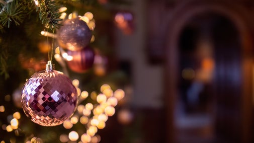 Pink and silver Christmas baubles on a tree, glowing with warm lights inside Felbrigg Hall
